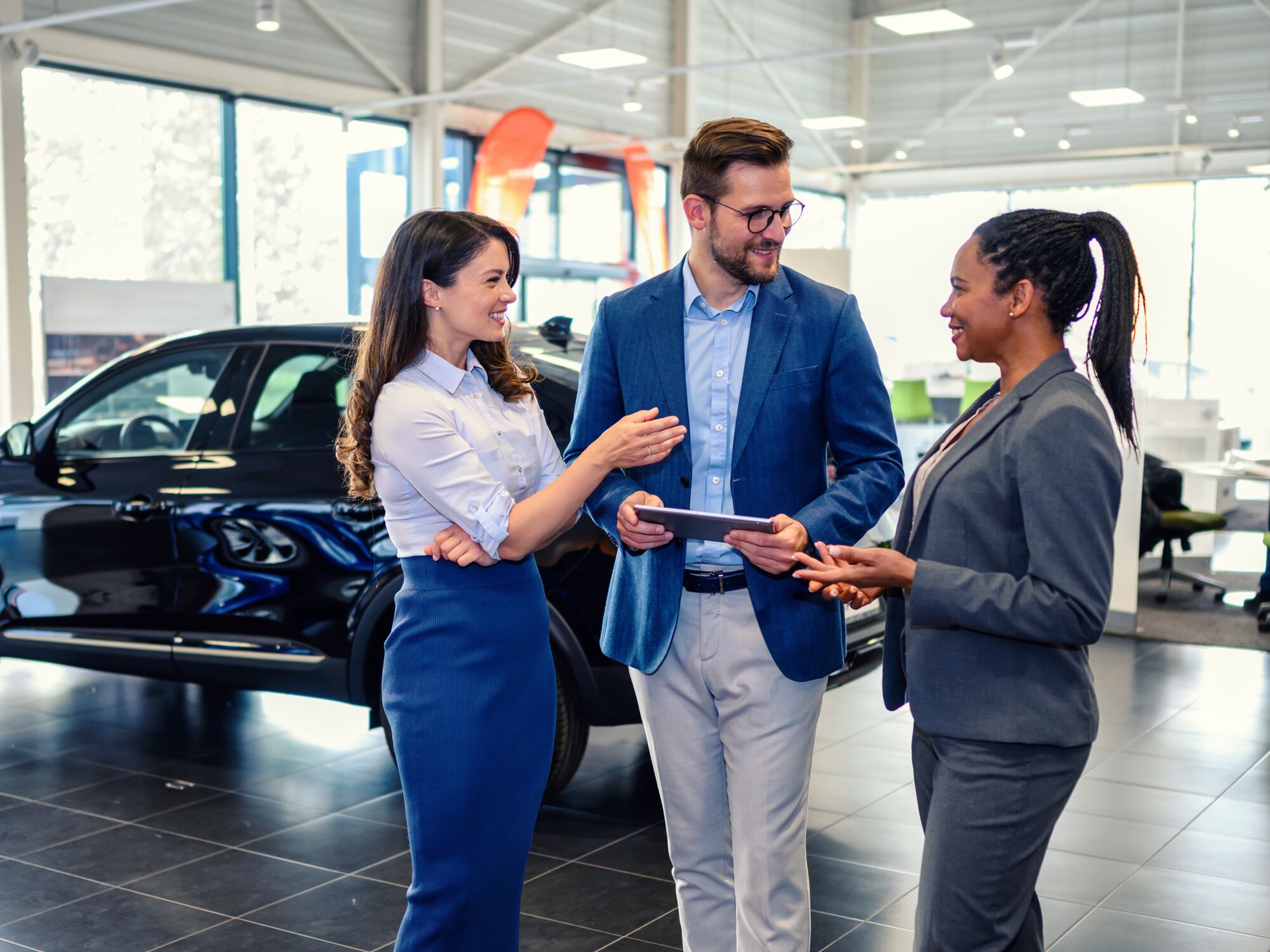 Happy business people talking in a car showroom.