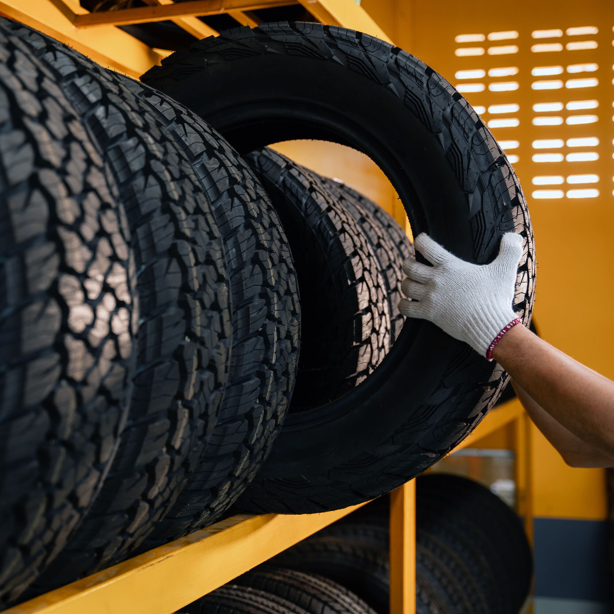 hand of a tire changer lifting a car tires out of a warehouse.