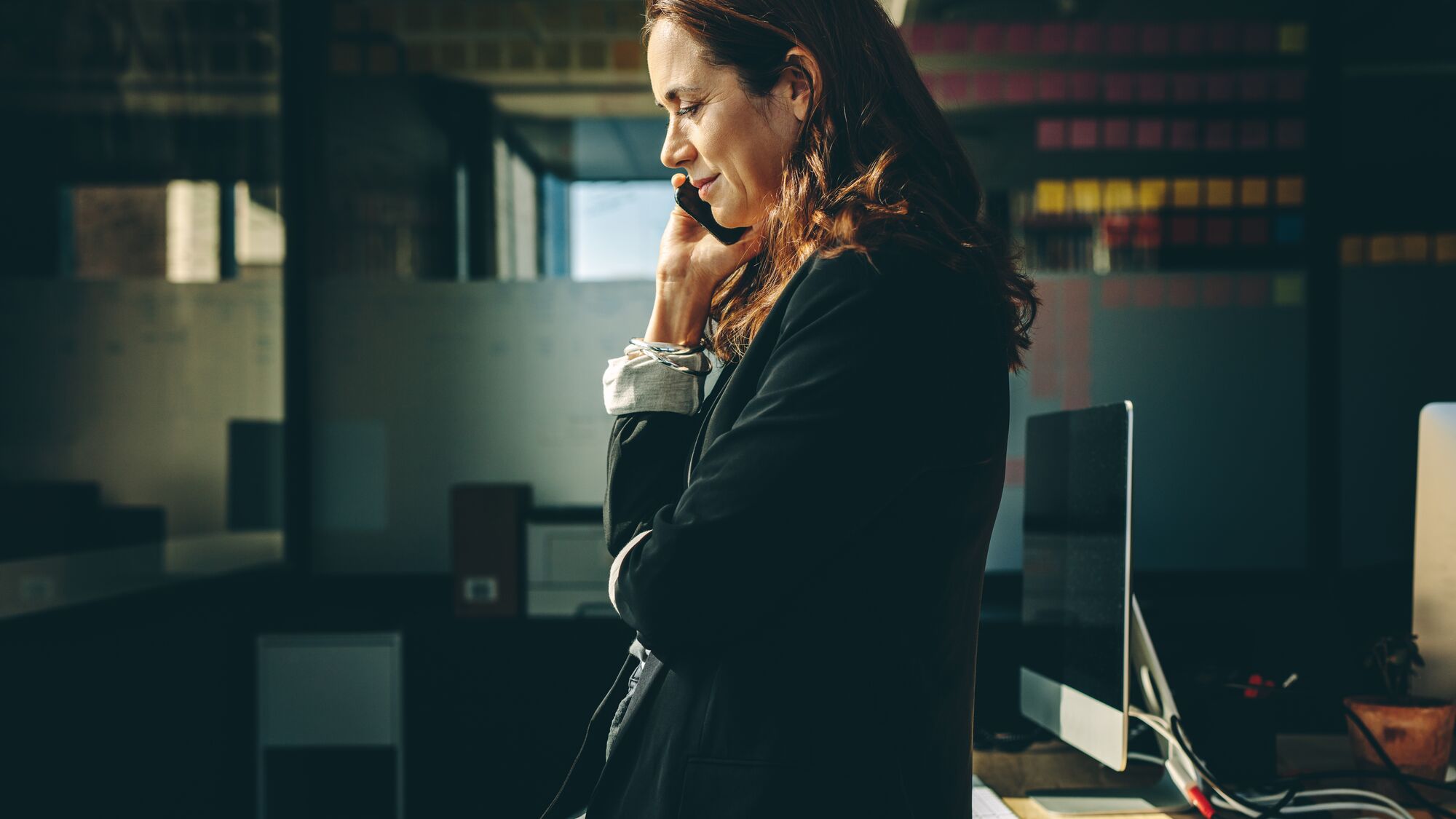 Side view of a businesswoman talking on mobile phone in office. Woman entrepreneur on a phone call in office.
