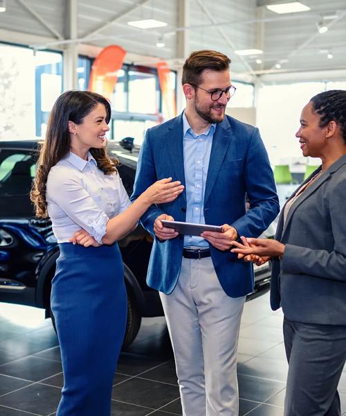 Happy business people talking in a car showroom.
