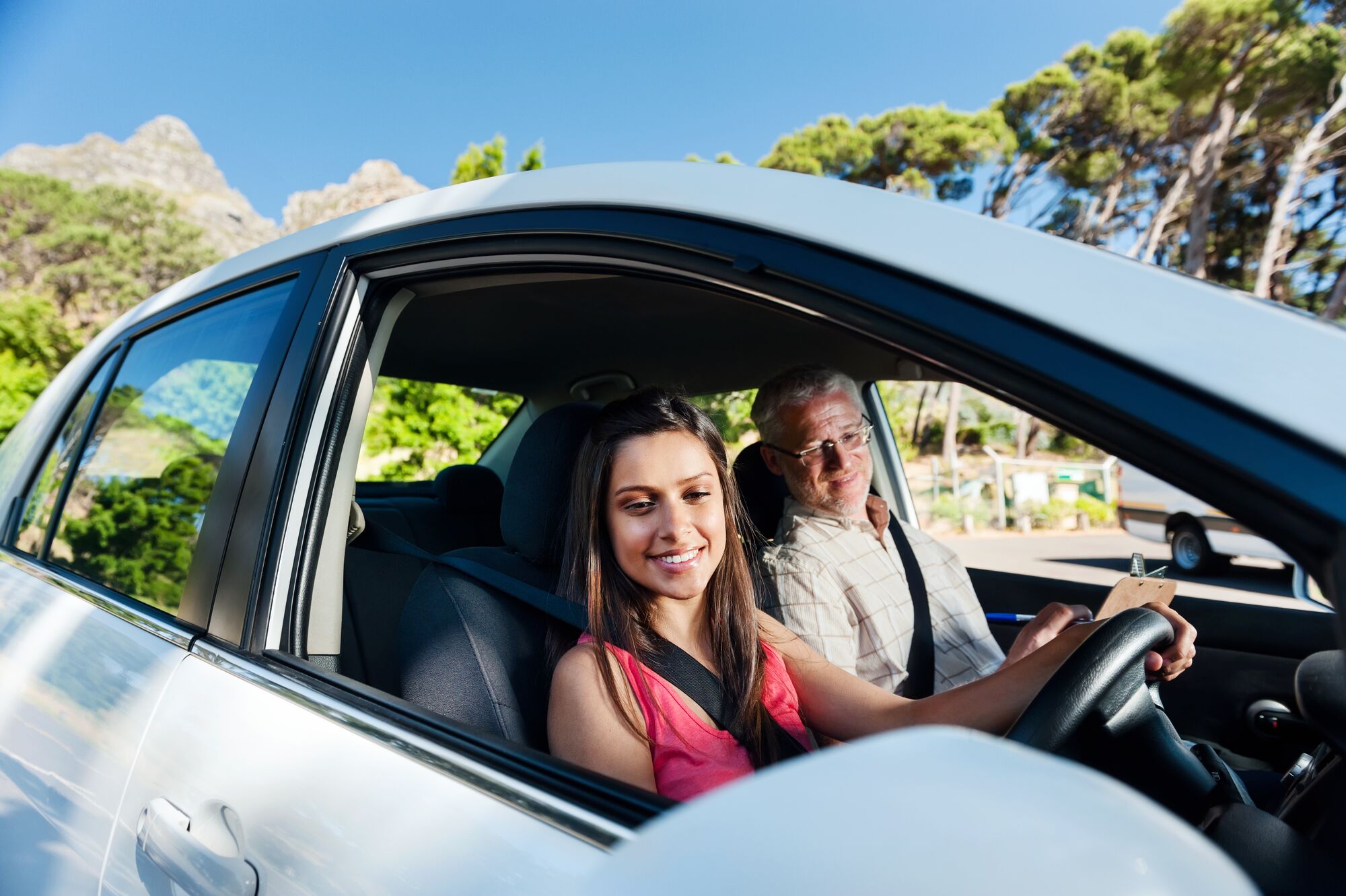 Learner driver student driving car with instructor. happy and confident smiling girl