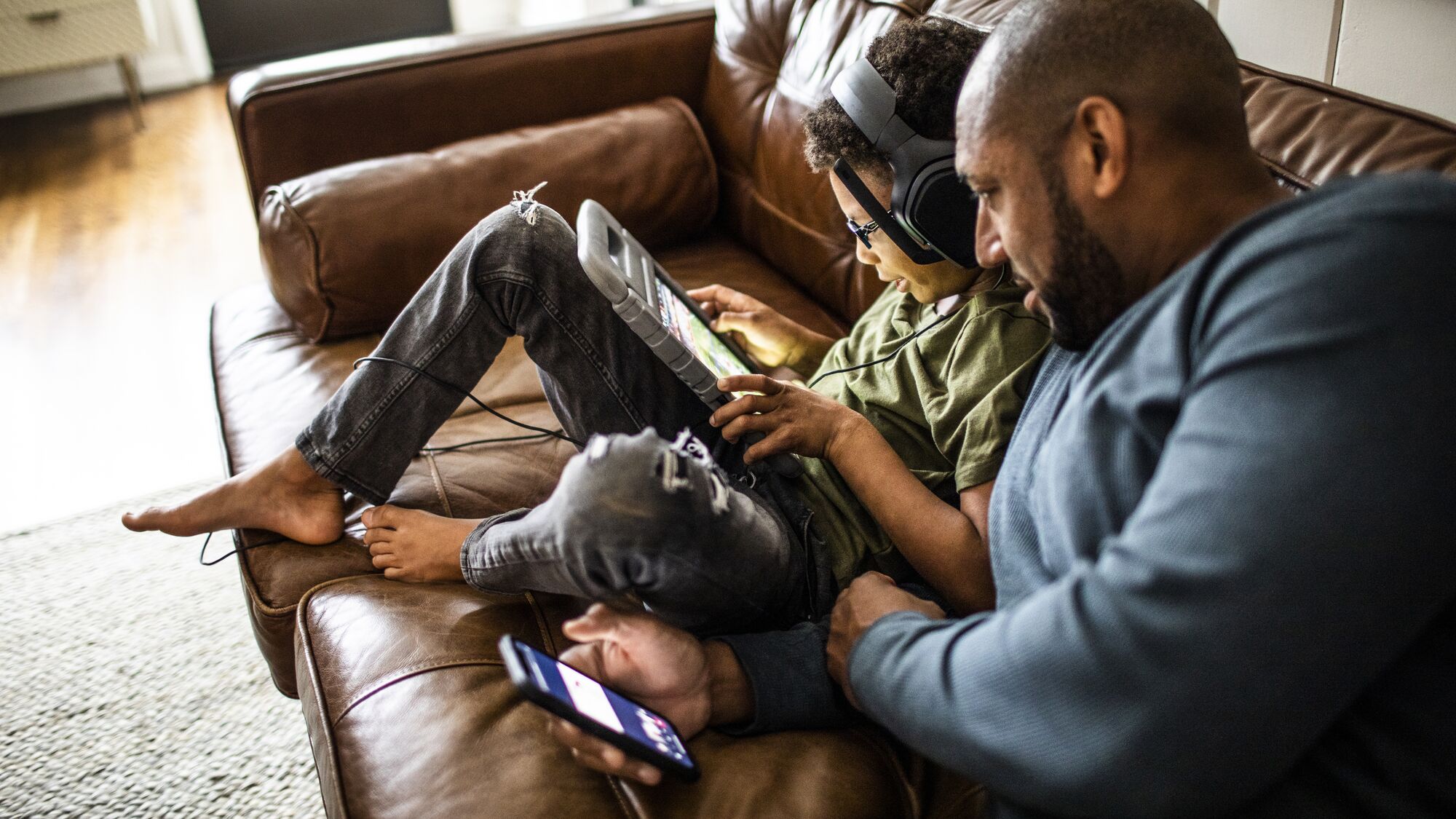Father and son using digital tablet on sofa