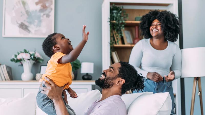 Shot of a happy loving family playing fun games in the living room at home. Mother, father and their boy playing together on the sofa at home.