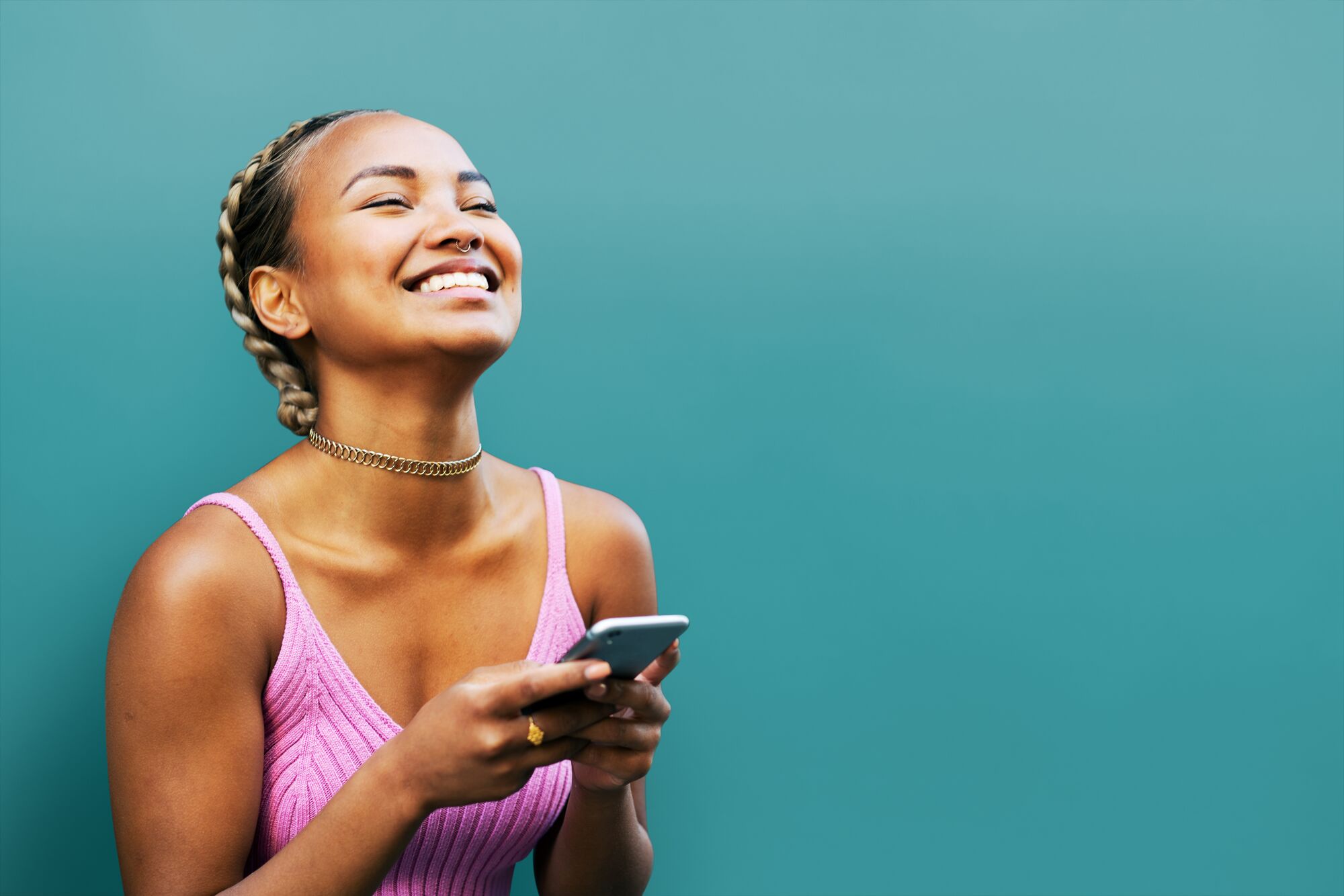 Woman with her phone in front of teal wall.
