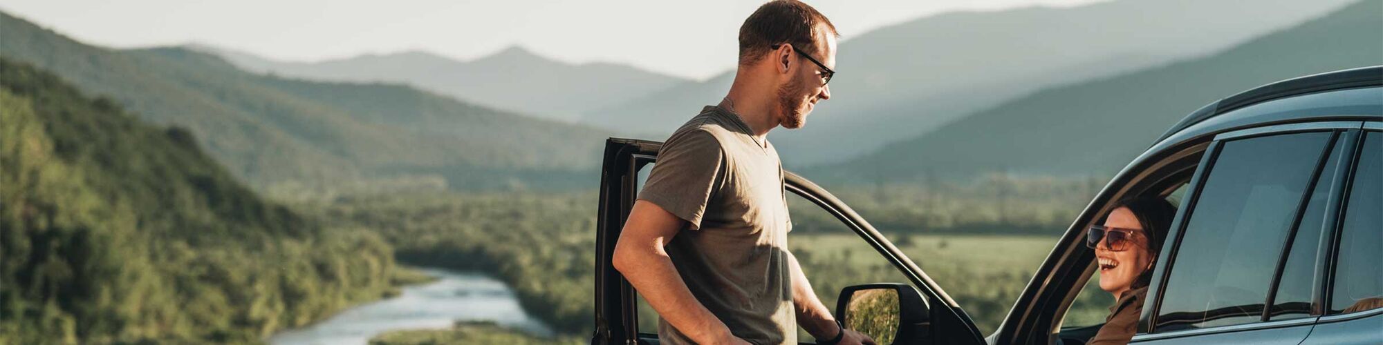 Man and Woman Enjoying Journey on Their Car Over Beautiful Landscape