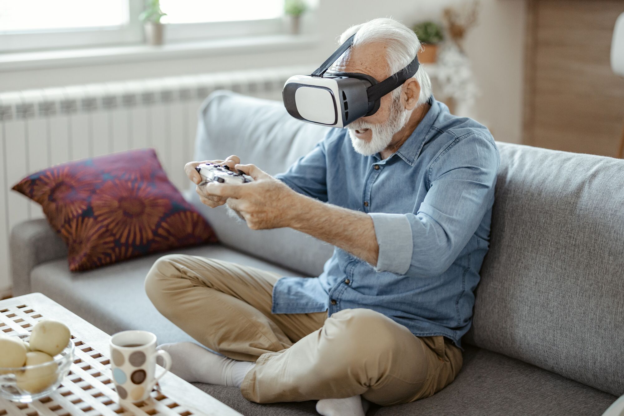 Bearded Senior Man Wearing Virtual Reality Headset and Holding Controllers Play in a Video Game at Home. Active Man Playing Vr Quest Adventure