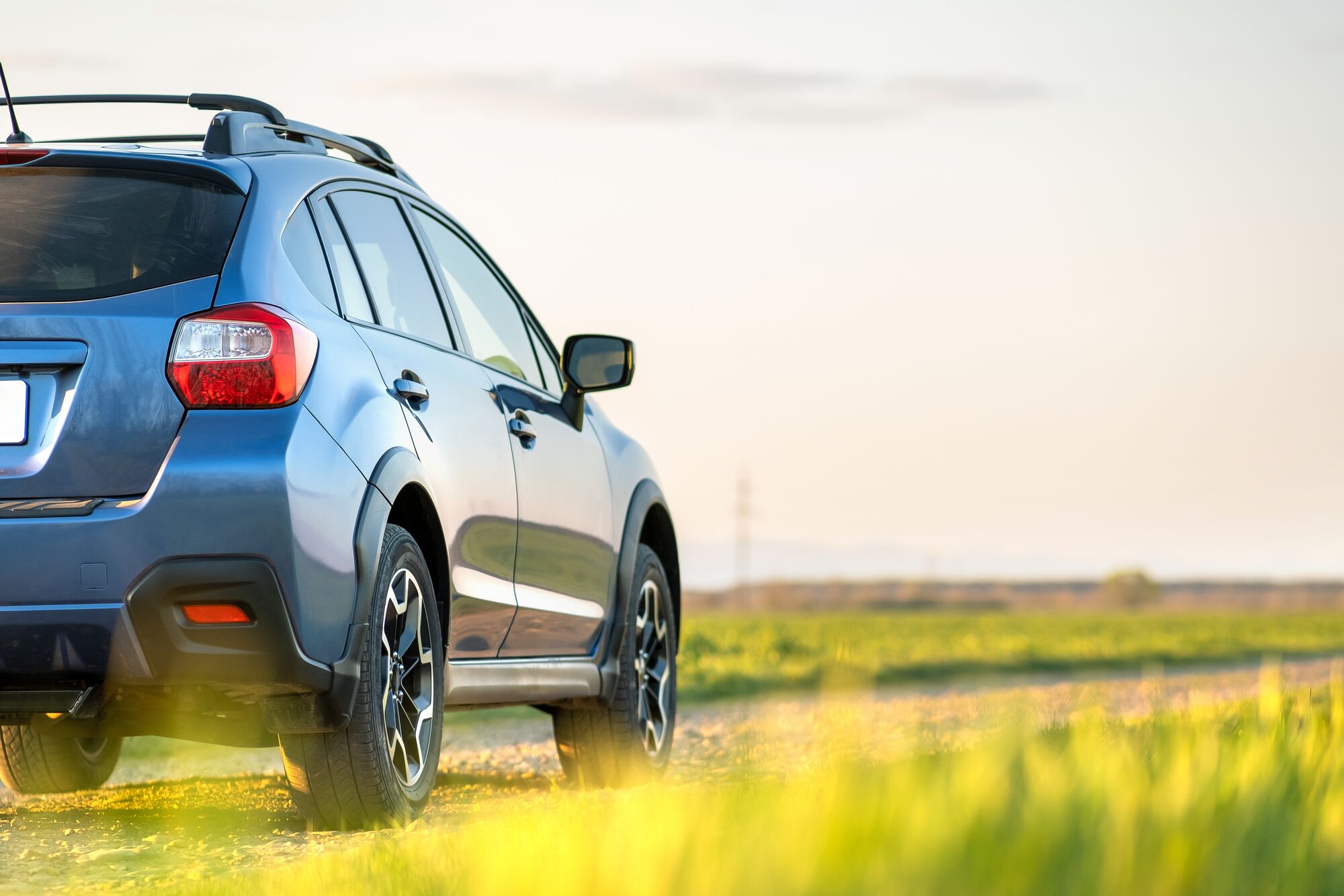 Landscape with blue off road car on gravel road. Traveling by auto, adventure in wildlife, expedition or extreme travel on a SUV automobile. Offroad 4x4 vehicle in field at sunrise.