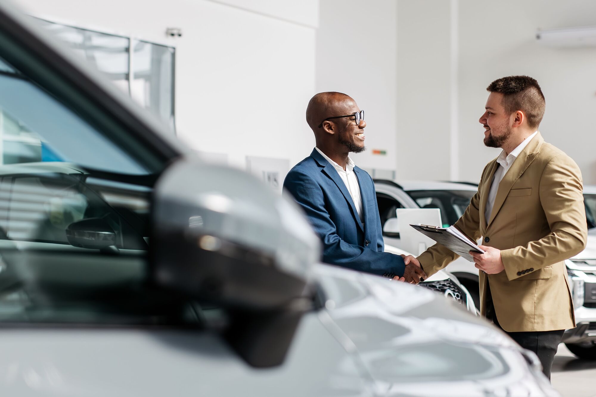 Auto F&I specialist (African-American) working together with auto dealership staff (caucasian)