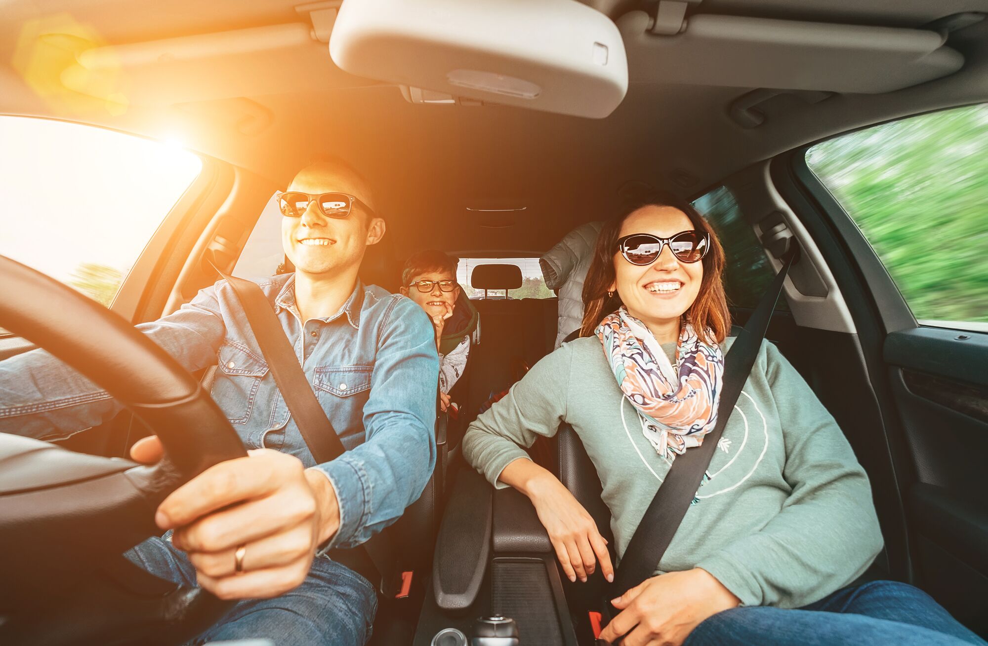 Young traditional family has a long auto journey and Cheerfully singing aloud the favorite song together. Safety riding car concept wide angle inside car view image.
