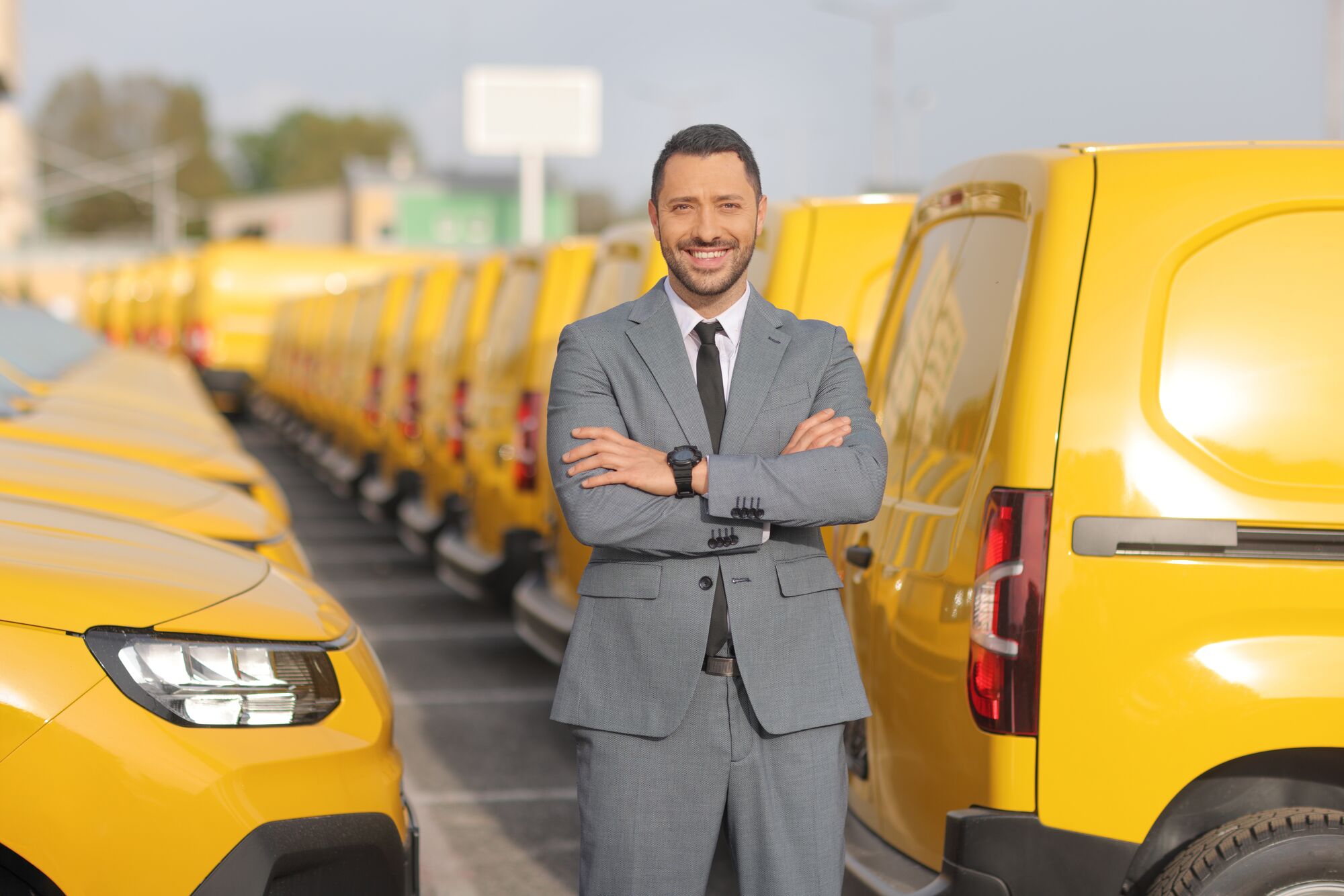 Commercial fleet manager standing in parking lot filled with light-duty yellow vans