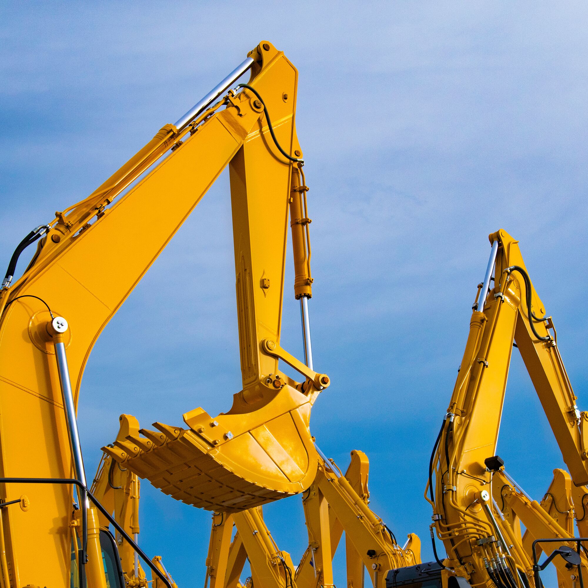 excavators heavy machinery yellow in the warehouse waiting to be assembled. Blue sky background.