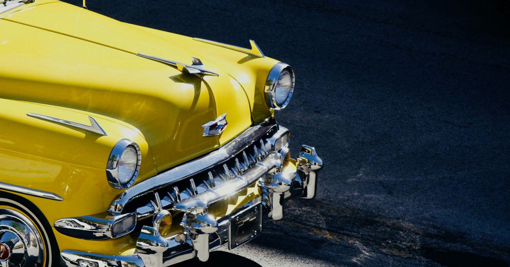 yellow classic car with chrome front grille and hubcaps
