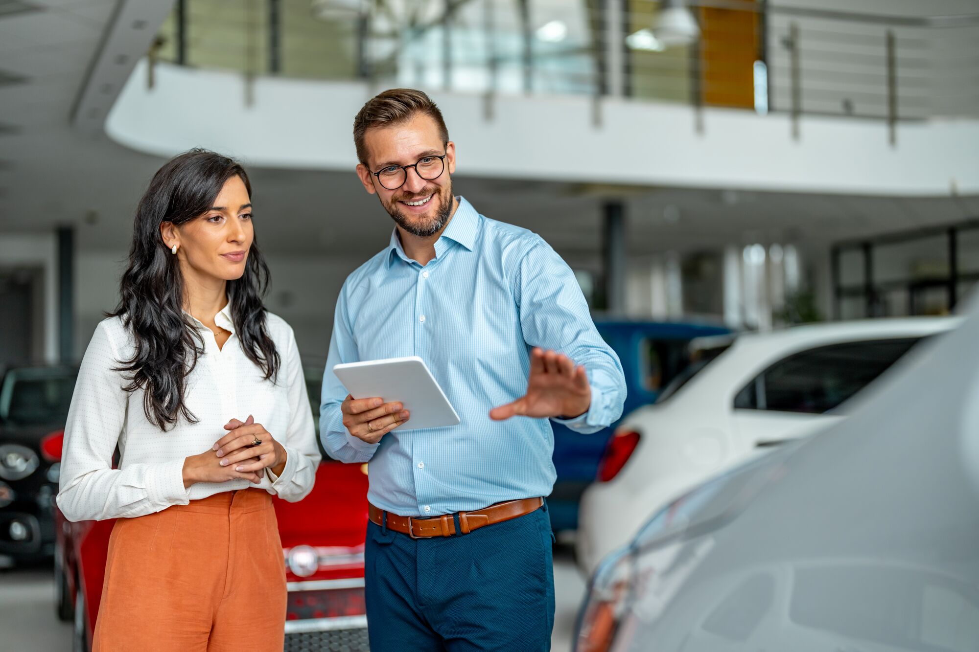 Salesman helping female customer to choose a new car