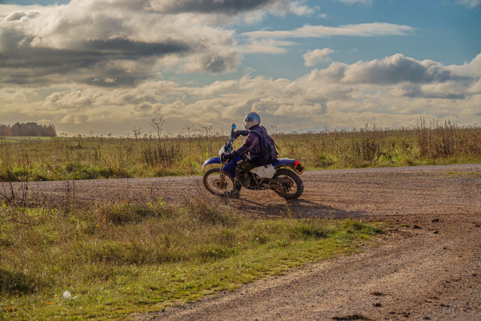 a motor cyclist (biker) riding his off-road motorbike along a stone track on Salisbury Plain, Wiltshire