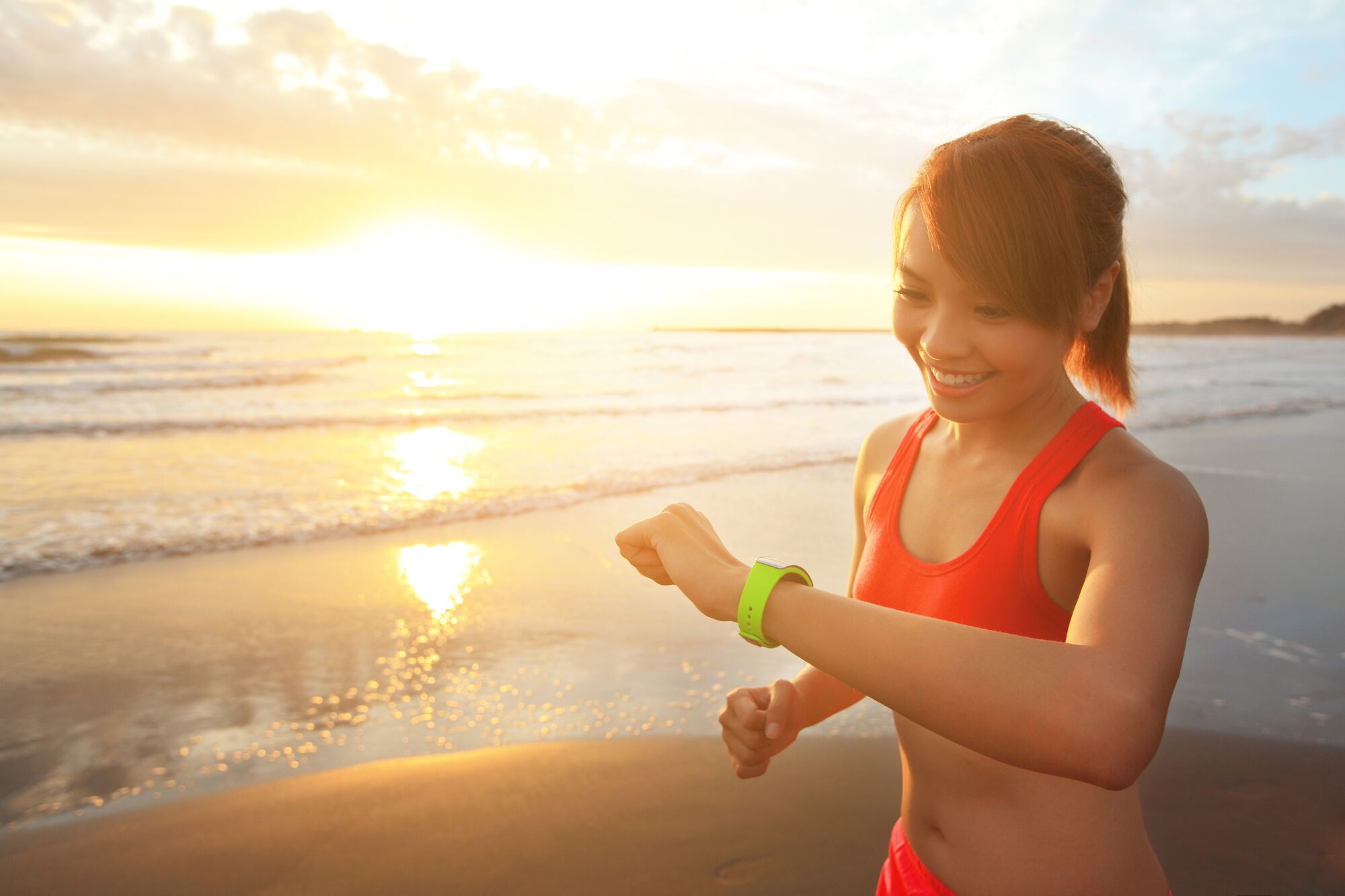 Woman exercising on beach with smart watch.