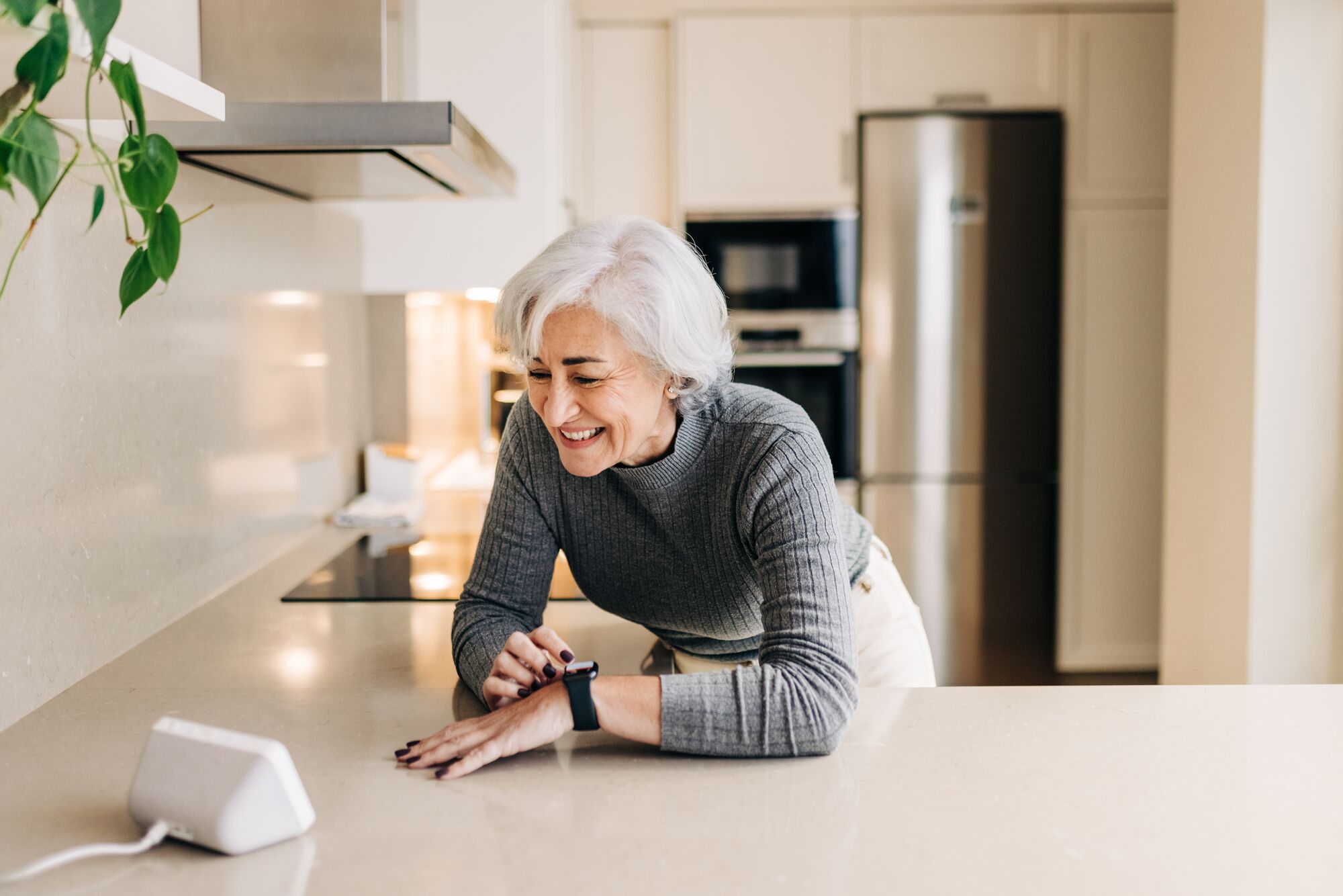 CL-DEVICES-SeniorLadySmartwatchSpeakerKitchen-GettyImages-1372299383